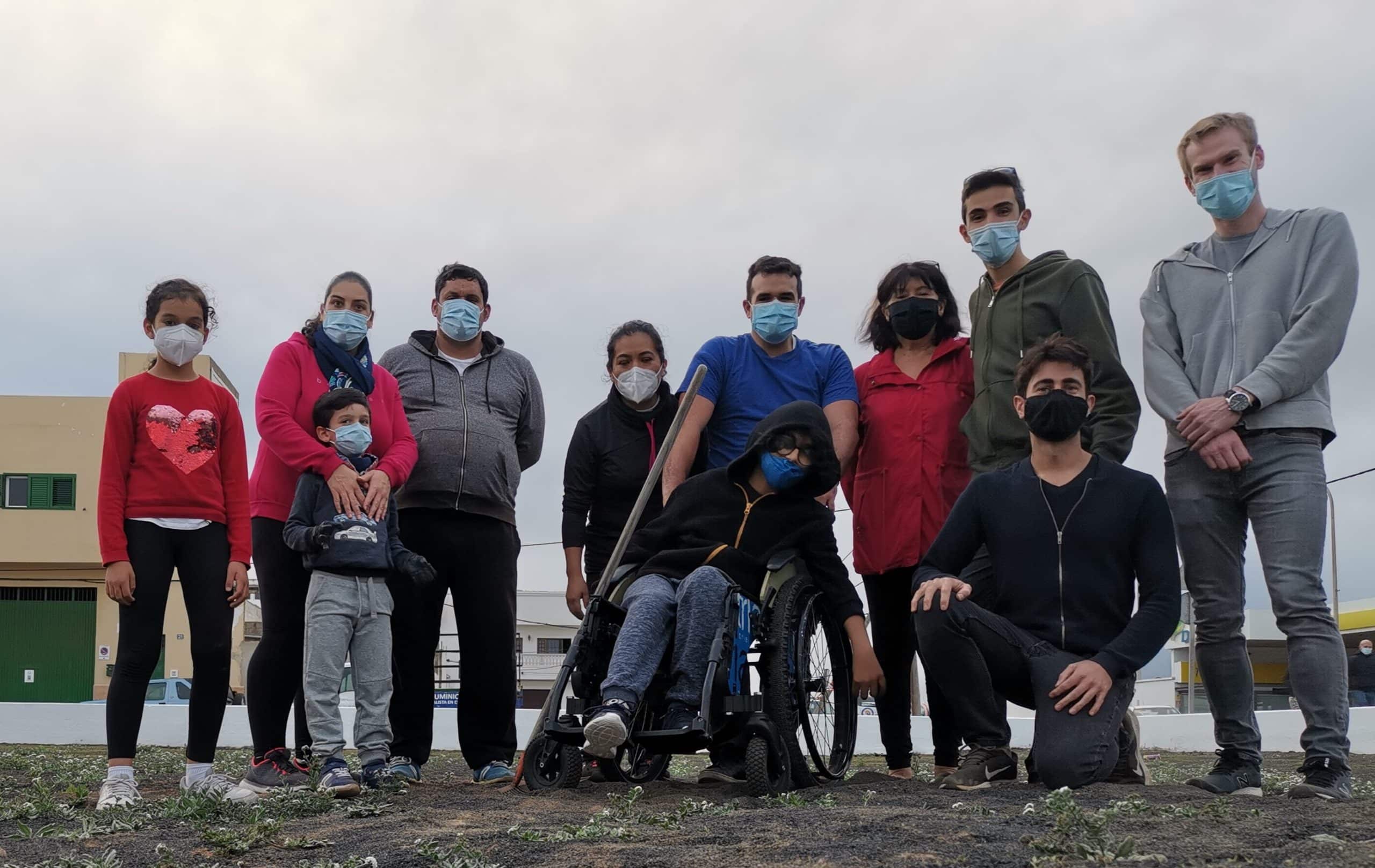 A group of people wearing masks standing in a community garden they just planted.