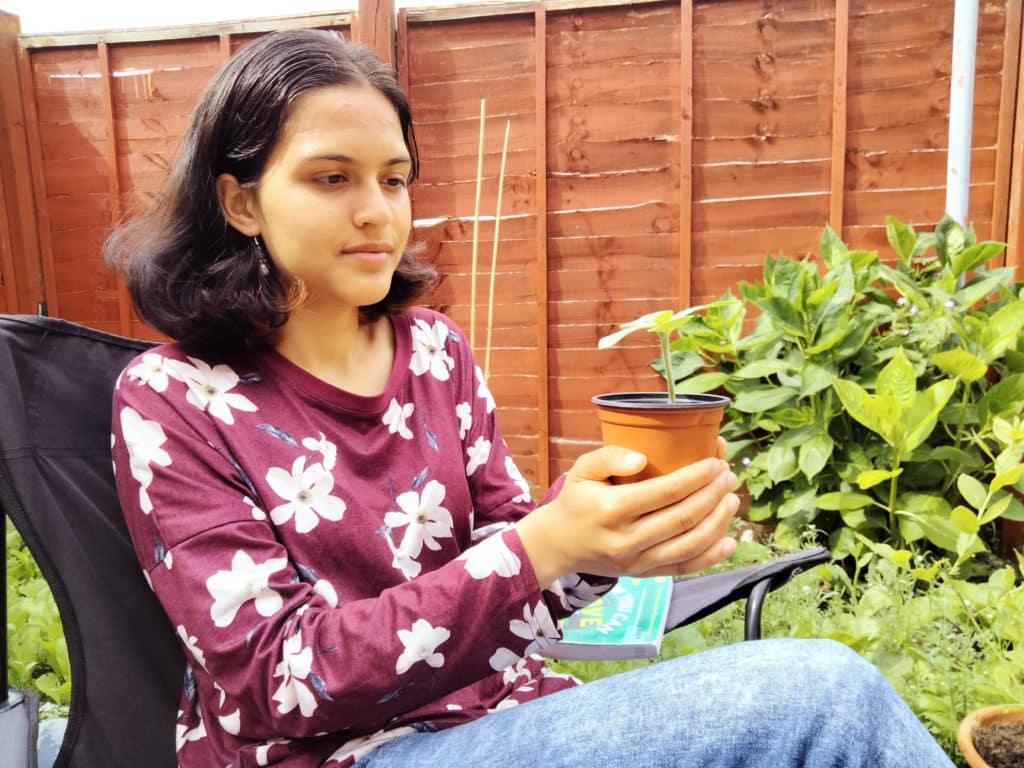 Hemlata holding a seedling in a pot