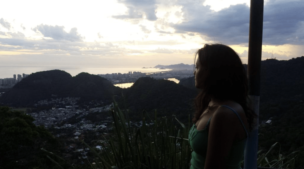 Larissa looking out over a mixed forest and urban landscape at sunset