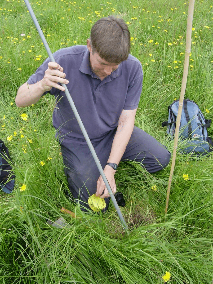 David Gowing measuring the depth of water table below a floodplain meadow by inserting a calibrated stick with a float-switch into a dipwell